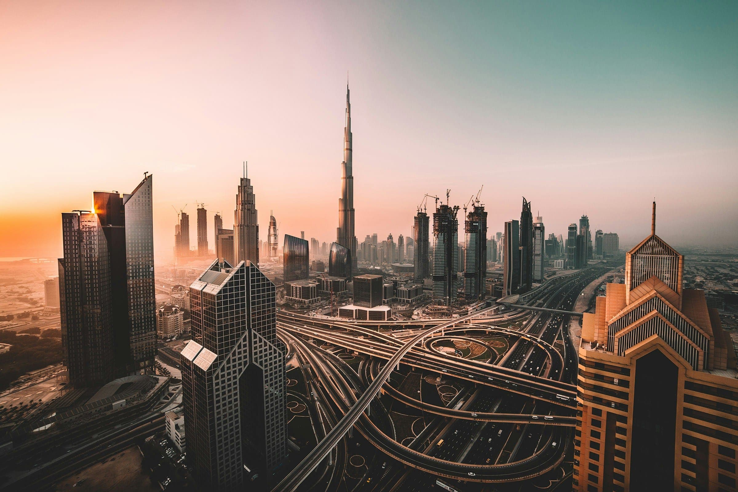Downtown Dubai at sunrise, with towers rising above a multi-level road interchange.